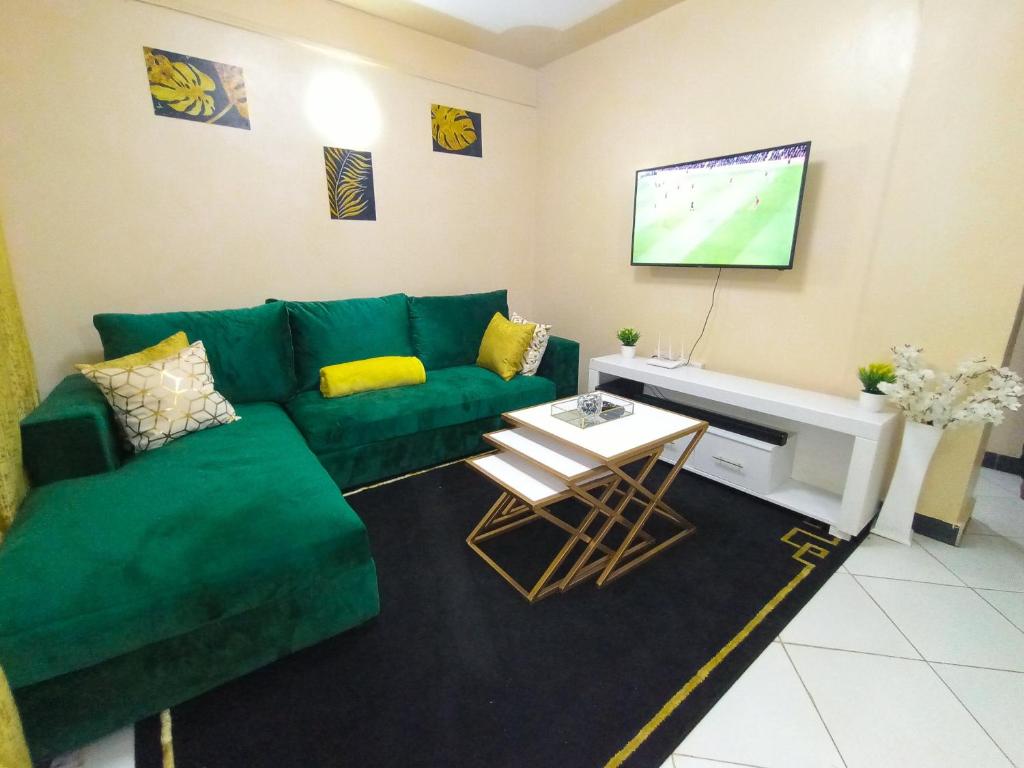 a living room with a green couch and a tv at The Ivy Suite- one bedroom 3 mins away from Ruiru Rainbow Resort in Ruiru