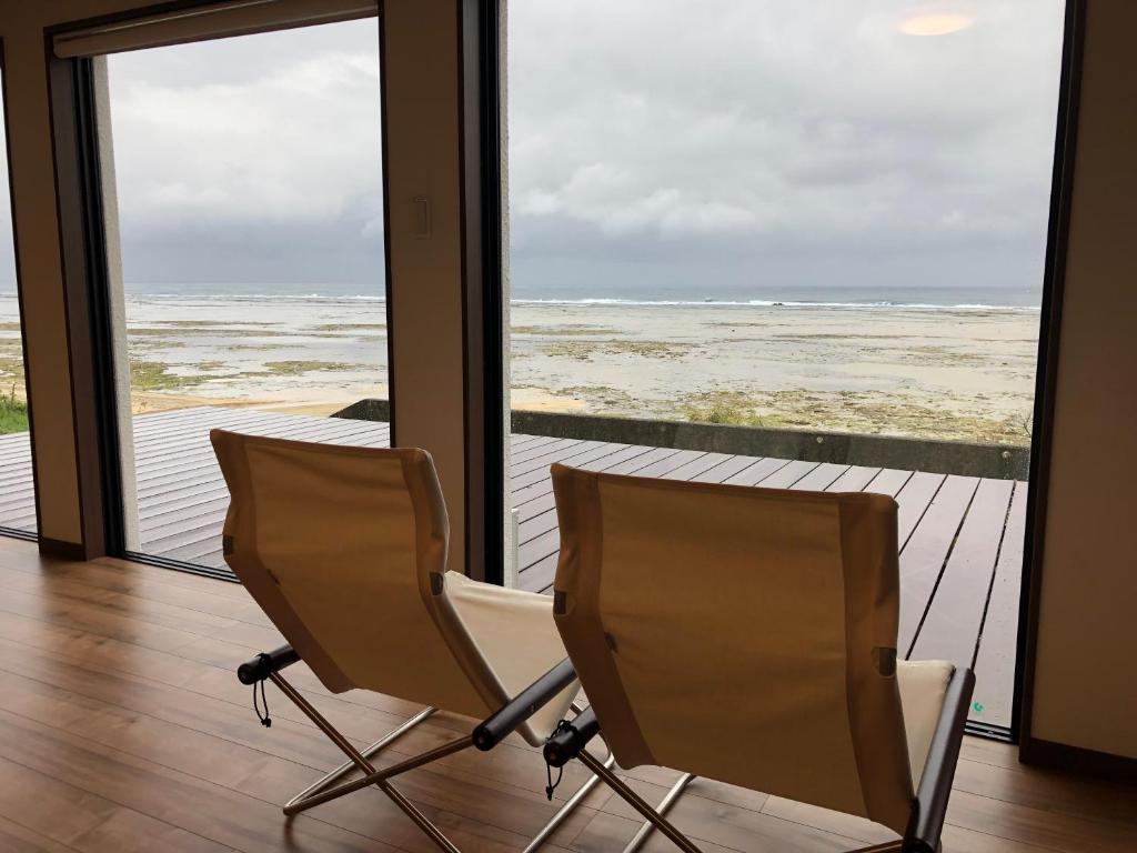 two chairs in a room with a view of the ocean at ゴールデンマイルヴィラ in Amami