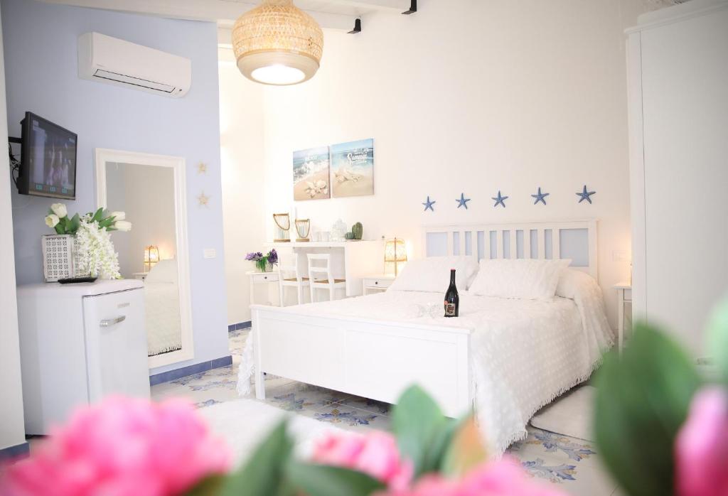um quarto branco com uma cama branca e uma garrafa de vinho em BLU MARE suite privata & apartment em Terrasini