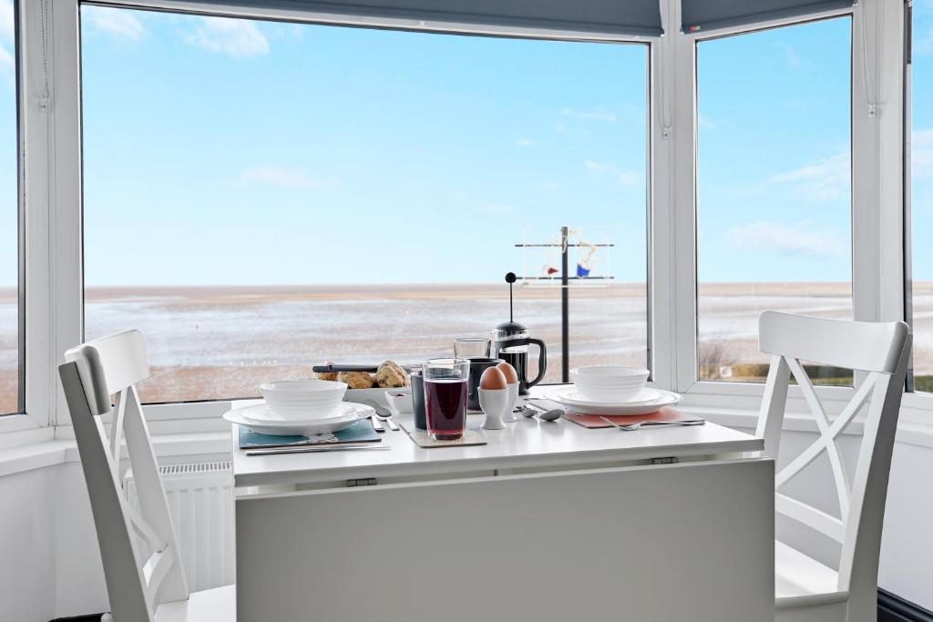 eine Küche mit einem Tisch und Stühlen sowie einem großen Fenster in der Unterkunft TYME Coastal Retreats - 1 and 2 Bedroom in Cleethorpes