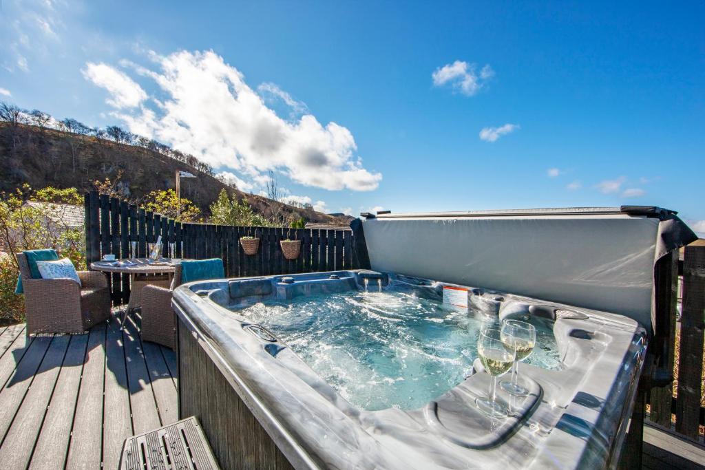 a hot tub on a deck with wine glasses at Katie's Flat in Oban