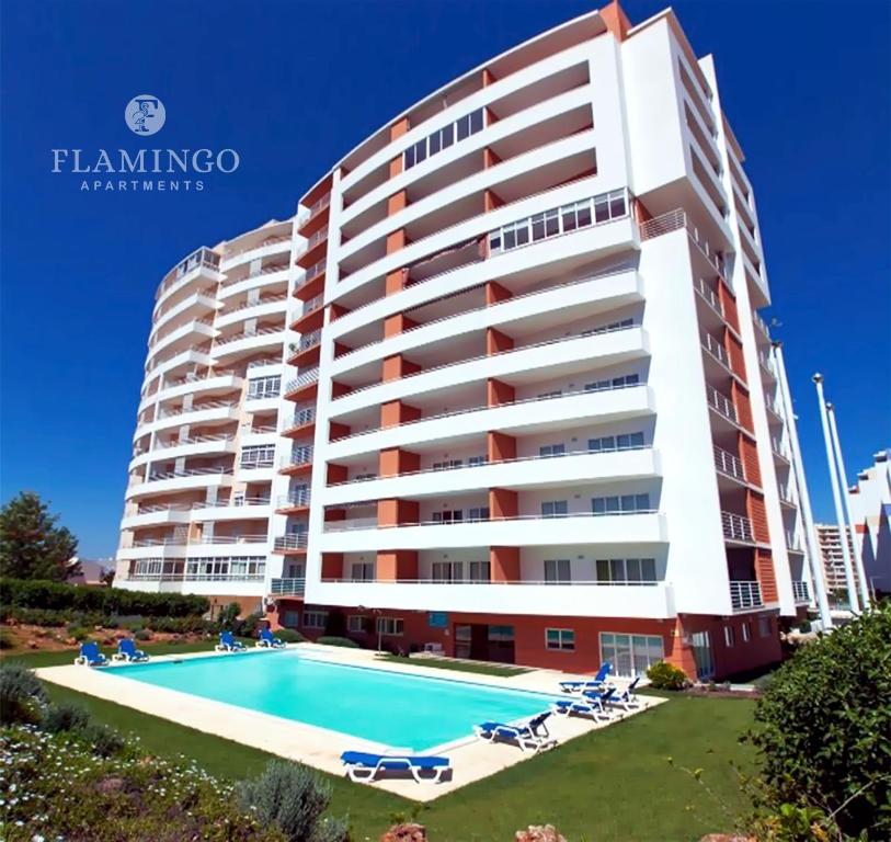 a large building with a swimming pool in front of it at Flamingo Apartments in Portimão