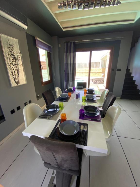 een eetkamer met een witte tafel en stoelen bij Purple Villa in Paralimni
