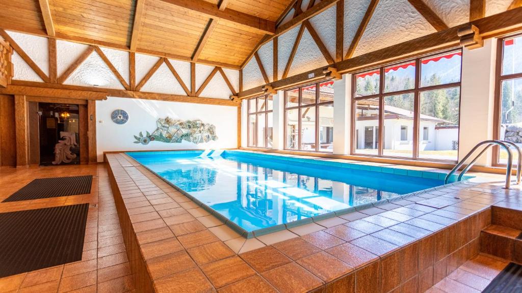 a large swimming pool in a house with windows at Aktivhotel & Gasthof Schmelz Ihr Urlaubs Hotel in Inzell mit Wellness Hallenbad, Alpensauna & Dampfbad in Inzell