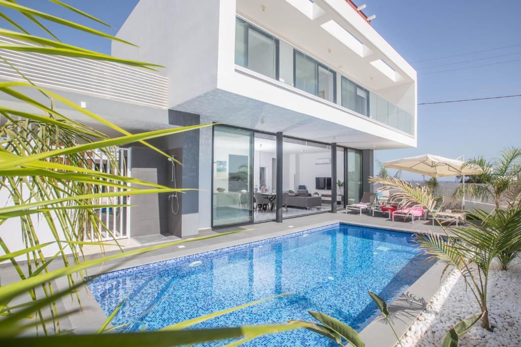 een villa met een zwembad en een huis bij Anassa Seaview Villa - Stunning Panoramic Views in Protaras