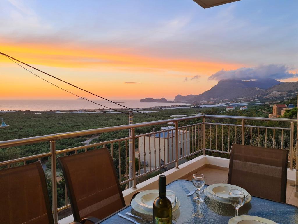 a table with a bottle of wine sitting on a balcony at New Villa Kalimera, view to Falasarna beach in Plátanos