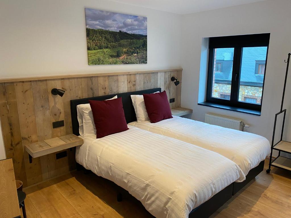 1 dormitorio con 1 cama con sábanas blancas y almohadas rojas en Rouleur Houffalize en Houffalize