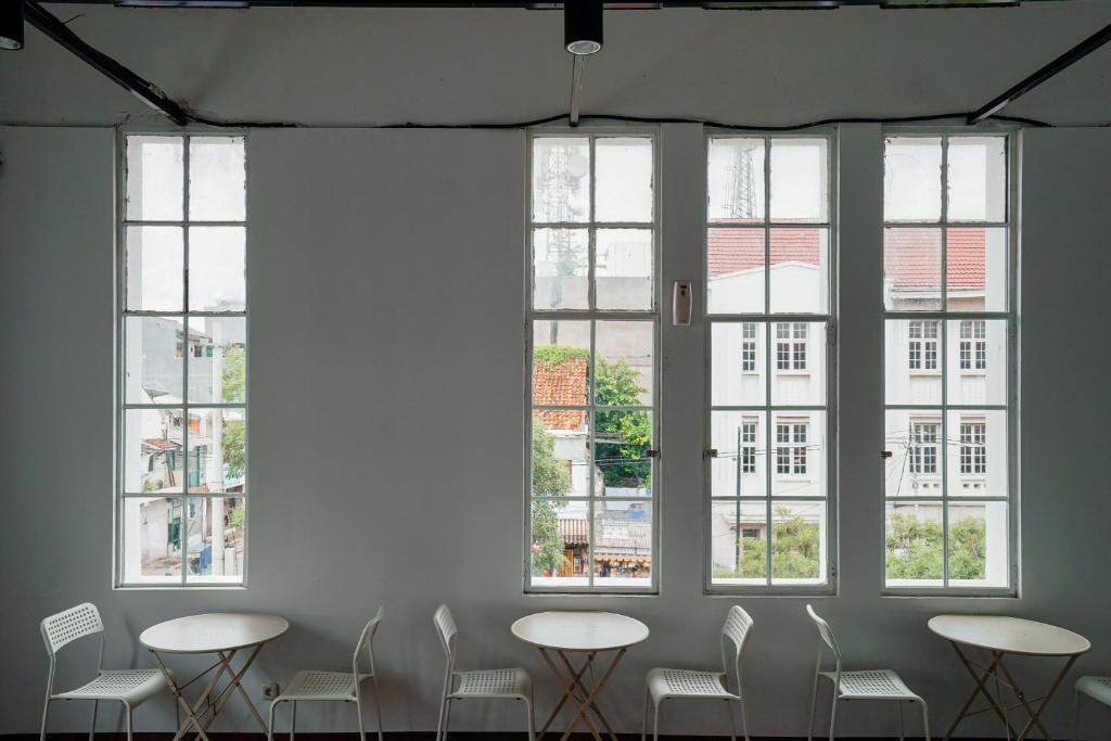 a room with tables and chairs and windows at Bobopod Kota Tua, Jakarta in Jakarta