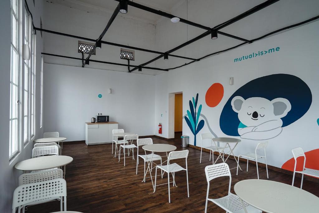 a room with tables and chairs and a teddy bear mural at Bobopod Kota Tua, Jakarta in Jakarta