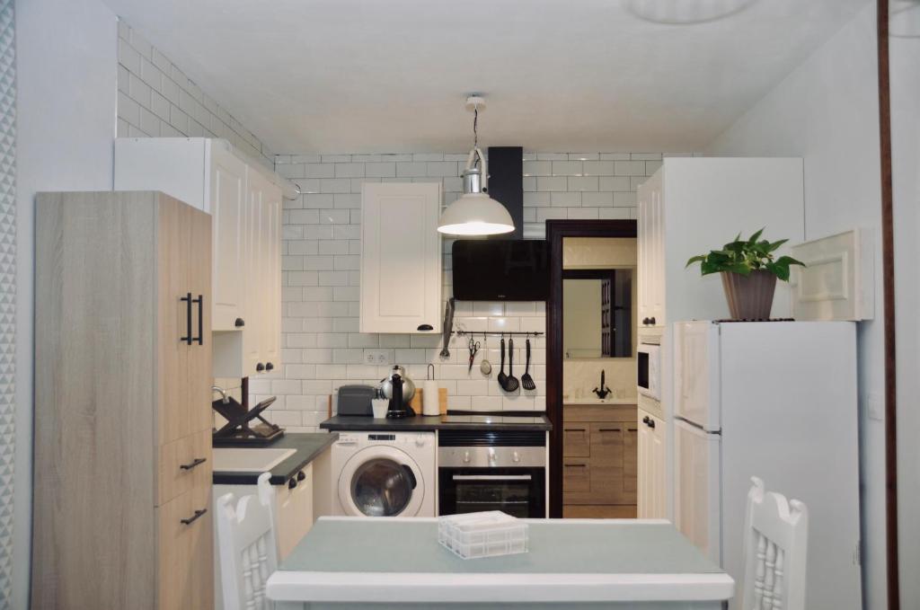 a kitchen with white cabinets and a white refrigerator at Apartamento Hiedra in Santillana del Mar