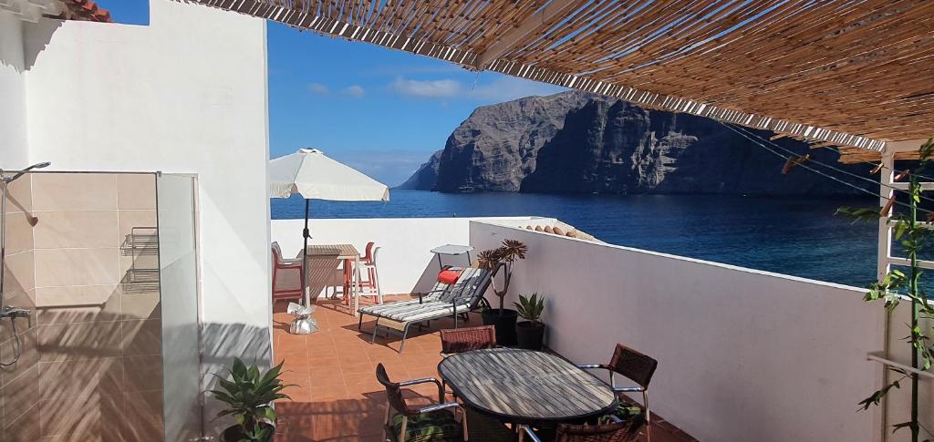 uma varanda com mesa e cadeiras e vista para a água em Penthouse de Roca in Poblado Marinero em Santiago del Teide