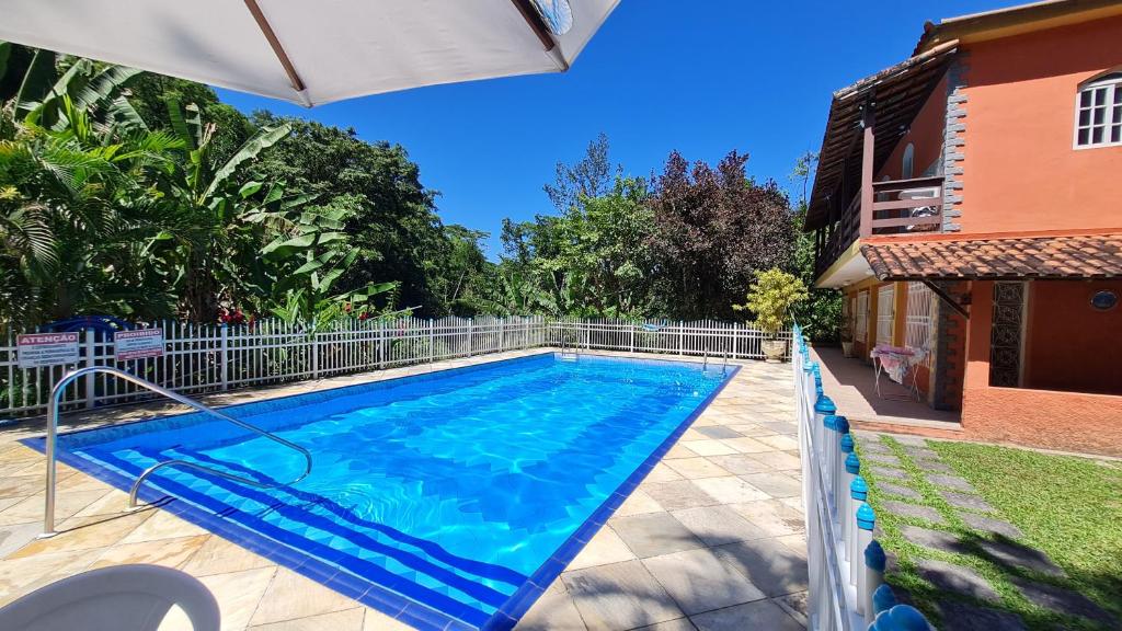 een zwembad met een parasol naast een huis bij Rancho Cravo e Canela - Guapimirim in Guapimirim