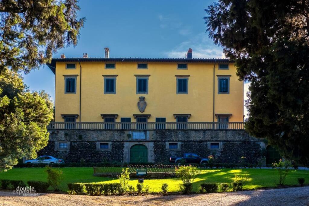 un gran edificio amarillo con coches estacionados frente a él en Villa Pandolfini 2, en Lastra a Signa