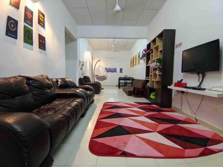 a living room with a leather couch and a rug at HOMESTAY DELISHA PARIT RAJA UTHM in Parit Raja