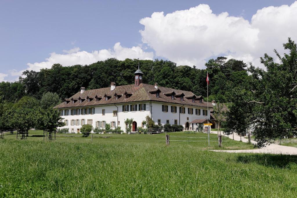 une grande maison blanche dans un champ arboré dans l'établissement Klosterhotel St. Petersinsel, à Sankt Petersinsel
