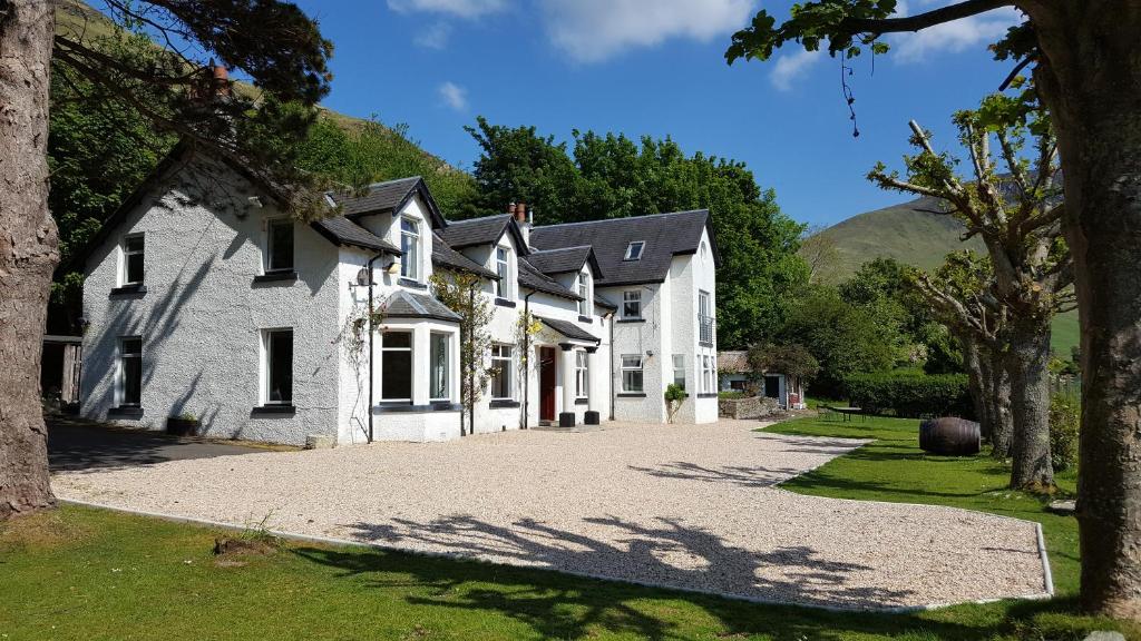 a large white house with a driveway at Butt Lodge in Lochranza