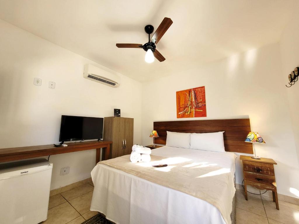 Un dormitorio con una cama y un ventilador de techo. en Pousada Casa Centro Búzios, en Búzios