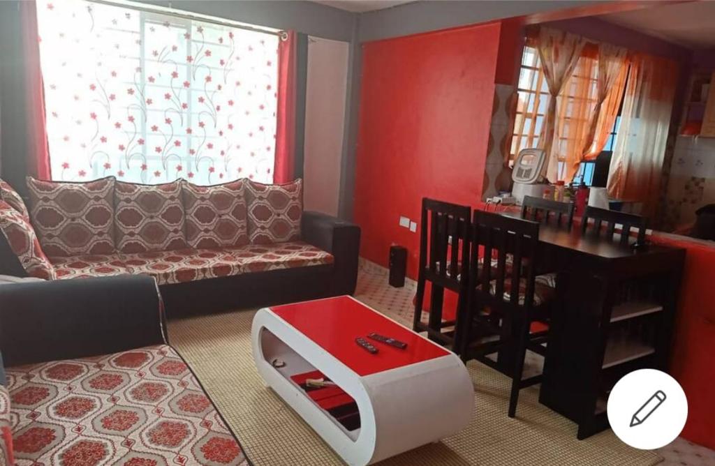 uma sala de estar com um sofá e uma mesa em Megs Place - Red - Embu Town em Embu