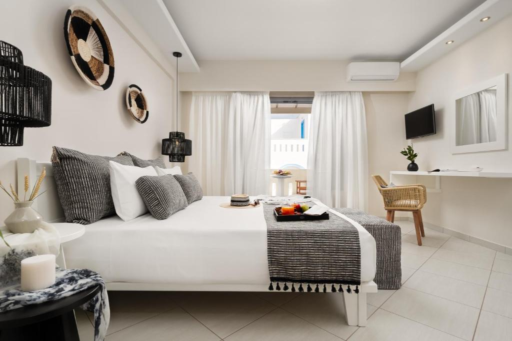 uma sala de estar com uma cama branca e uma mesa em Ormos Holiday Studios em Naxos Chora