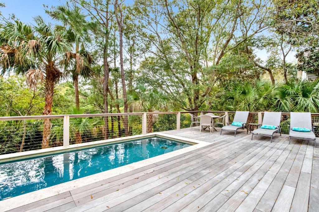 a deck with a pool and two chairs and a table at Bufflehead 3 in Kiawah Island