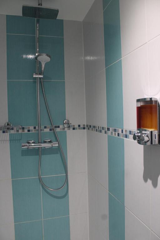 La salle de bains est pourvue d'une douche avec du carrelage bleu et blanc. dans l'établissement L'Escale, chambres chez l'habitant, au Mans