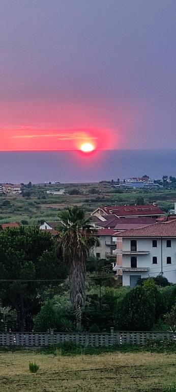 einen Sonnenuntergang mit einer Palme vor einem Gebäude in der Unterkunft Case Perrone in Grisolia