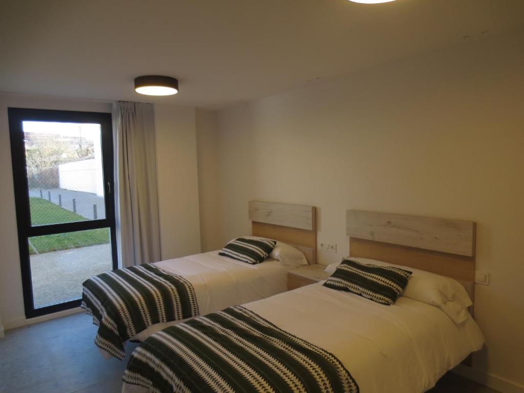 two beds in a room with a window at Apartamentos Hispano Nájera in Nájera