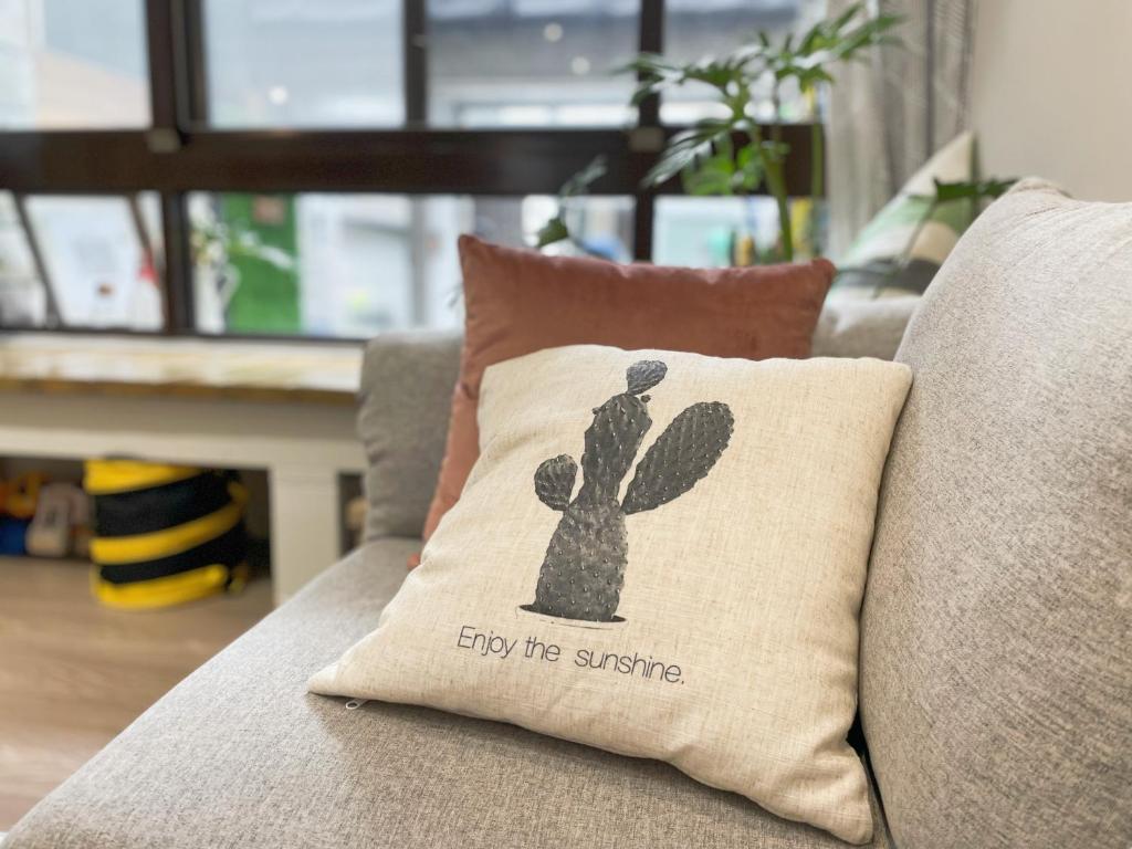 Una almohada de cactus en un sofá con las palabras disfruta del sol en LeeHo B&B 李何寓所 en Hualien