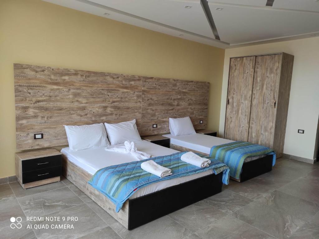 a bedroom with two beds and a wooden wall at pyramids view suite/vista piramidi in Cairo