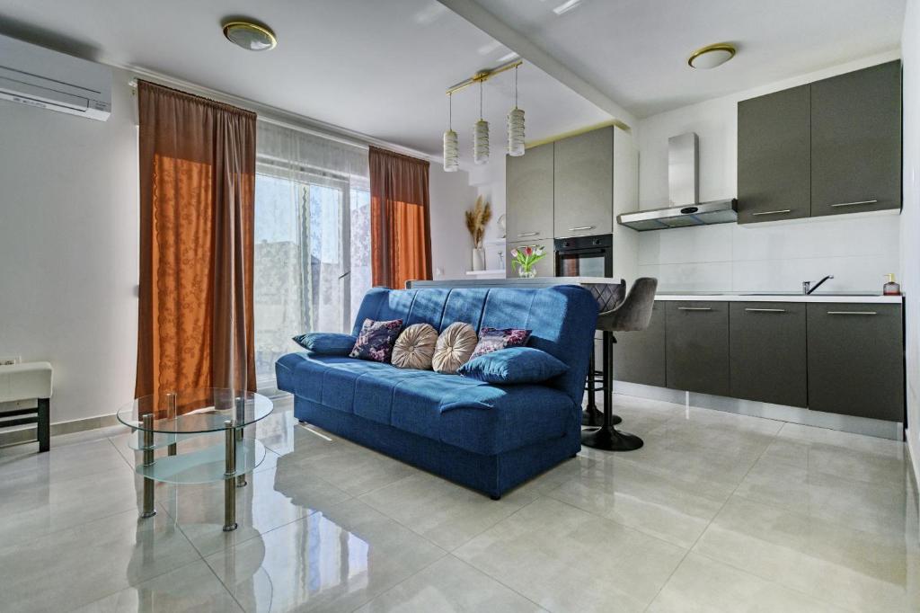 een woonkamer met een blauwe bank en een keuken bij Holiday apartment Zadar - with summer balcony and parking in Zadar