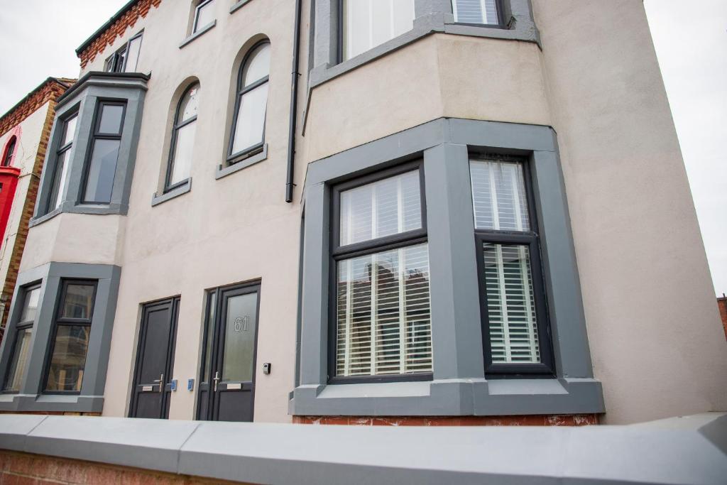 una casa con ventanas negras y persianas blancas en Withnell Stays - Apartment One - Ground Floor en Blackpool