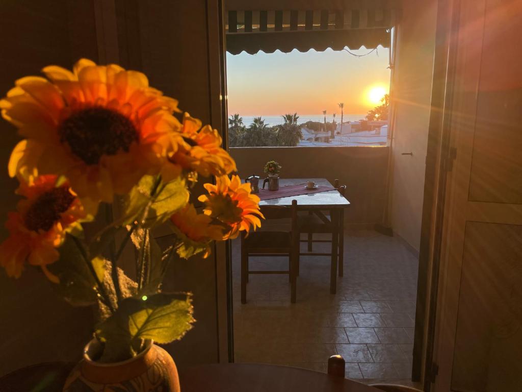 un vaso di fiori seduto su un tavolo con il tramonto di Baia Verde Accomodation a Baia Verde