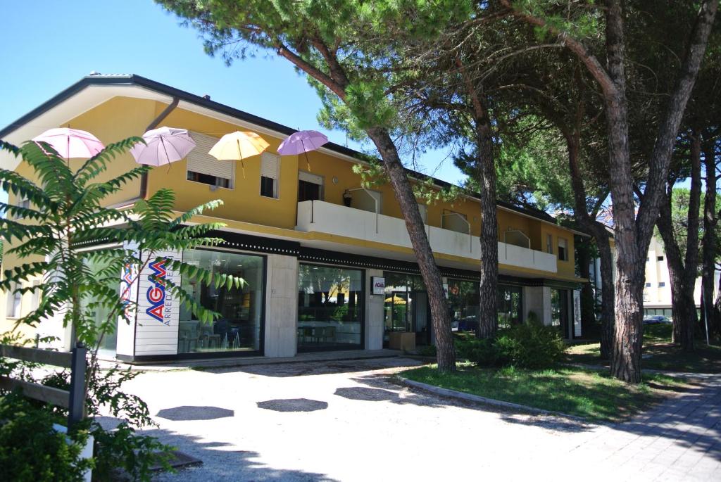 a yellow building with umbrellas in front of it at Condominio LISA in Lignano Sabbiadoro