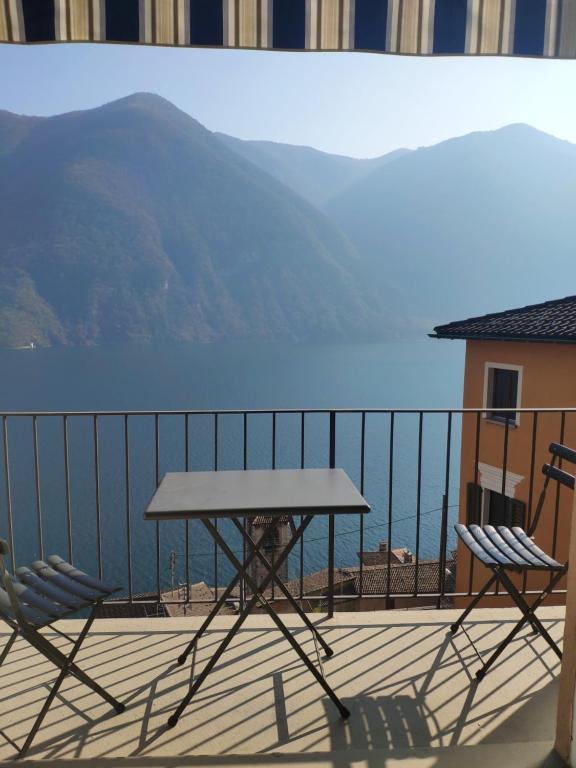 una mesa y sillas en un balcón con vistas al agua en Ristorante le bucce di Gandria en Gandria