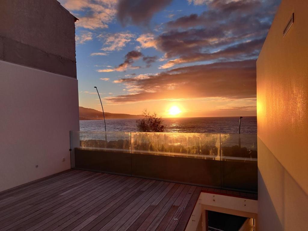 een balkon met uitzicht op de oceaan bij zonsondergang bij Barrocas Villas Azores in São Roque