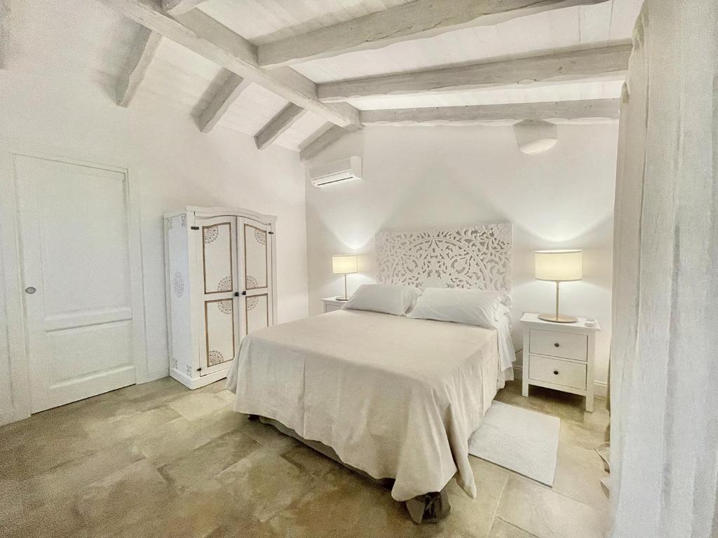 a white bedroom with a white bed and two lamps at Sea Love in Olbia