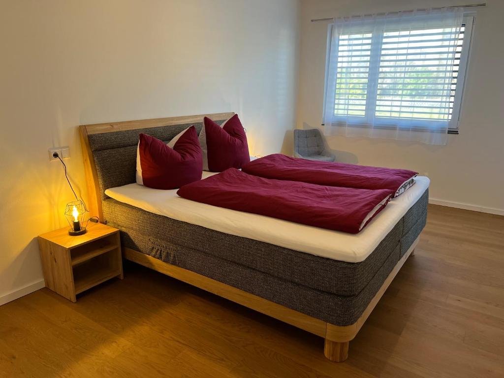 a bedroom with a bed with red pillows and a window at See-Eck in Überlingen