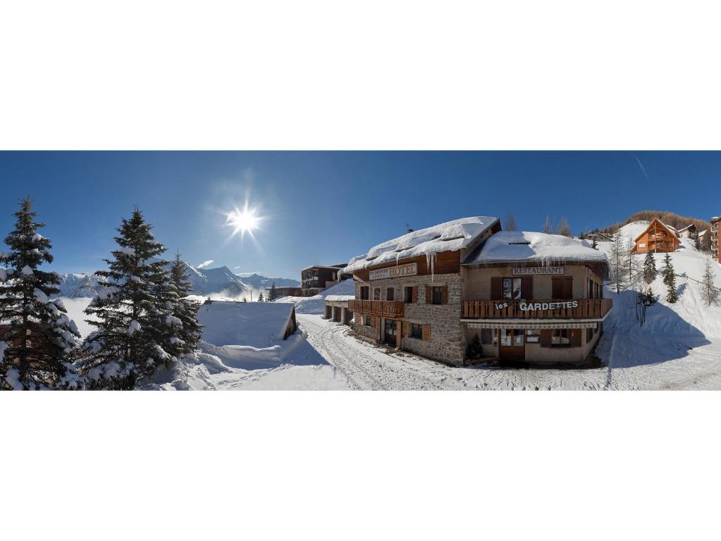 une maison dans la neige avec le soleil derrière elle dans l'établissement Hôtel les Gardettes, à Orcières