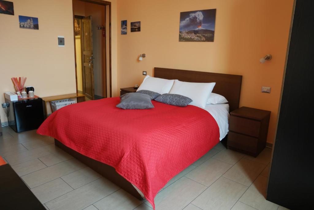 a bedroom with a bed with a red blanket at Jonio B&B in Acireale