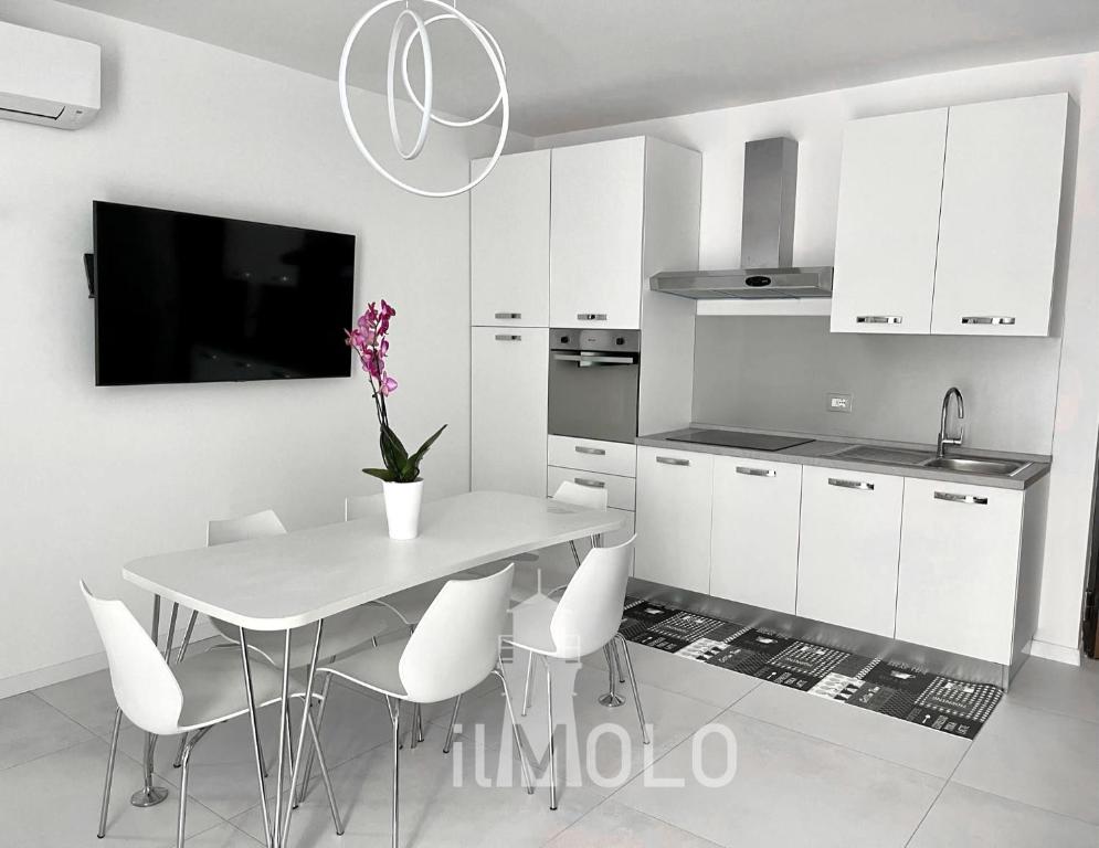 uma cozinha com uma mesa com cadeiras brancas e uma televisão em Il Molo em Nápoles