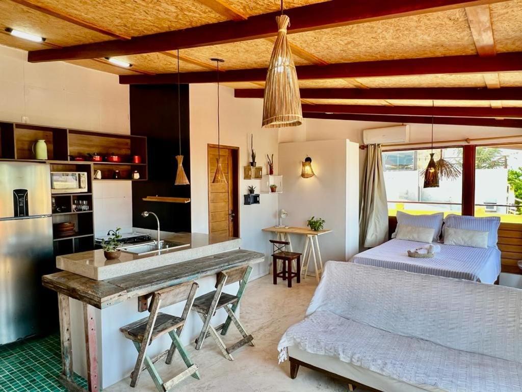 a living room with a bed and a kitchen at Apê do Fabiano Flats e lofts in Jericoacoara