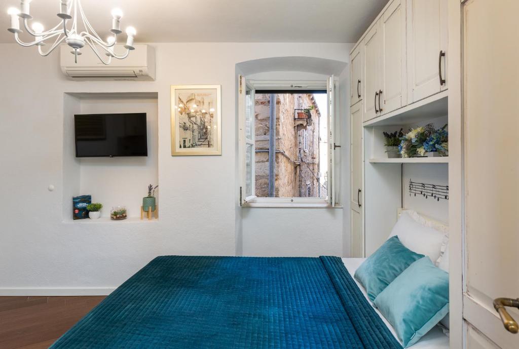 Un dormitorio con una cama azul y una ventana en Apartments Sounds of Dubrovnik, en Dubrovnik