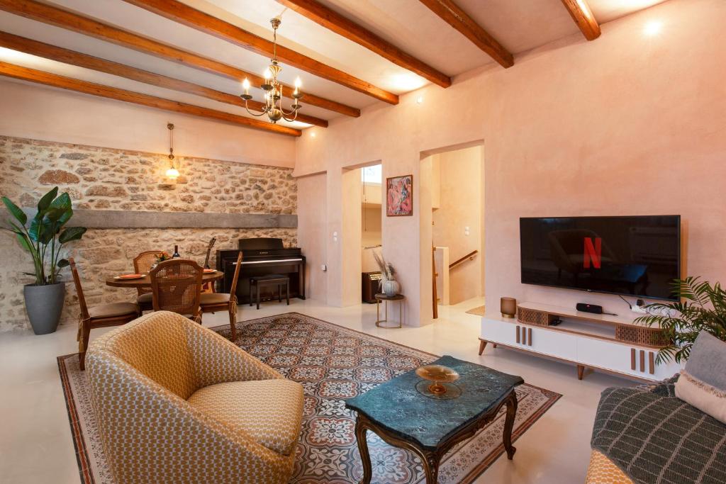 ein Wohnzimmer mit einem TV, einem Sofa und einem Tisch in der Unterkunft Casa Emiliana in Rhodos (Stadt)