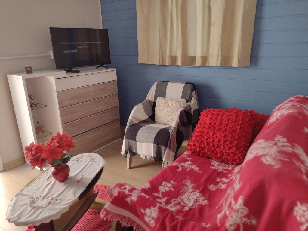Zimmer mit einem Bett, einem TV und einem Stuhl in der Unterkunft Kitnet Namorados in Gramado