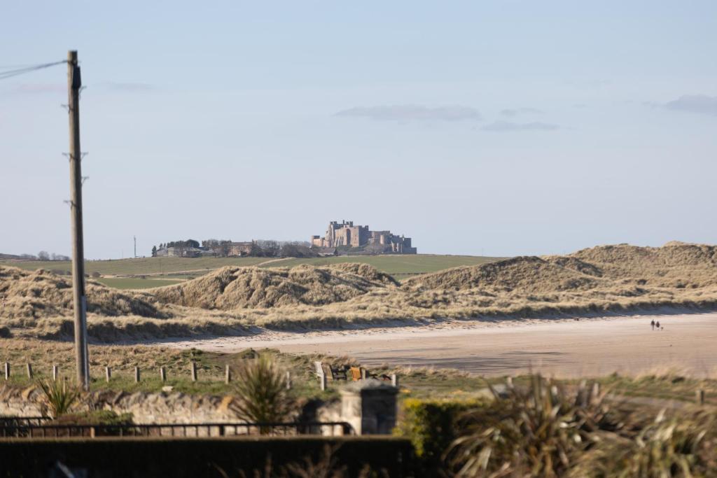 a view of a beach with a castle in the background at Beach House Hotel in Seahouses