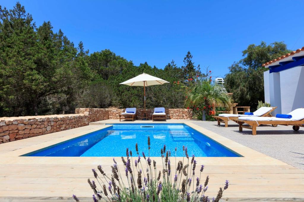 een zwembad met 2 stoelen en een parasol bij Finca Can Carlets in Cala Saona
