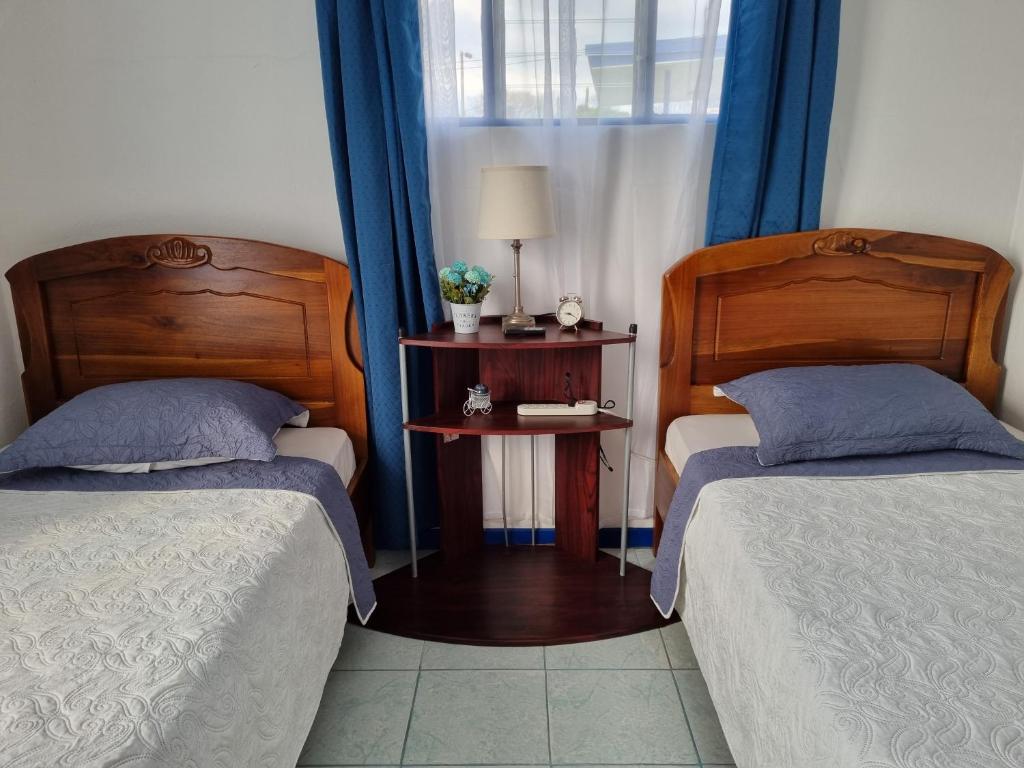 ein Schlafzimmer mit 2 Betten und einem Tisch mit einer Lampe in der Unterkunft Entire Homy apartment for you, 5 min SJO Airport in Alajuela