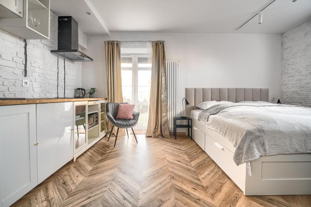 a white bedroom with a bed and a kitchen at Apartamenty MUNN 1 Szczecin in Szczecin