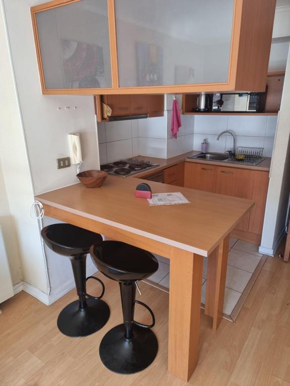 a kitchen with a wooden table and two bar stools at Precioso apartamento 1D+1B // Jumbo+centro 5 min in Puerto Montt