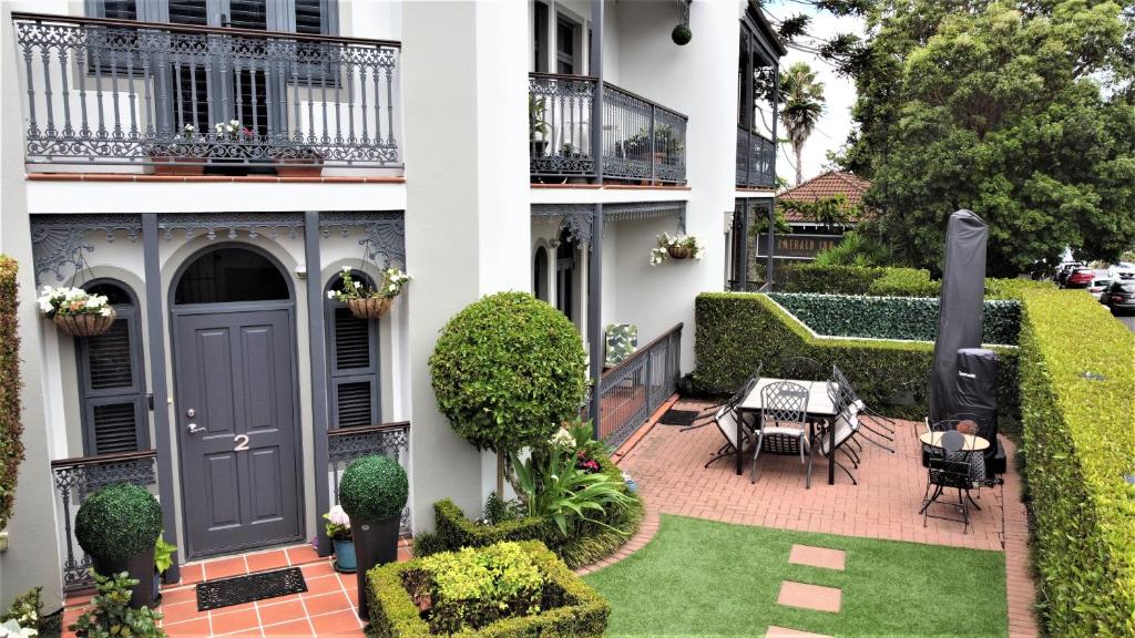 a white building with a black door and a patio at Takapuna Accommodation in Auckland